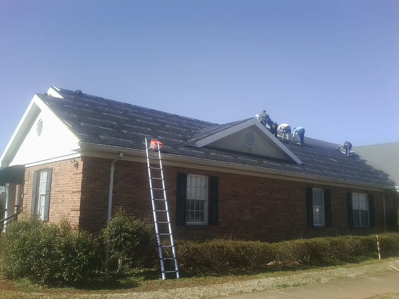 Crew tearing shingles off a brick ranch roof with a ladder set — Metal Roof Repair work by our crew in Elizabeth