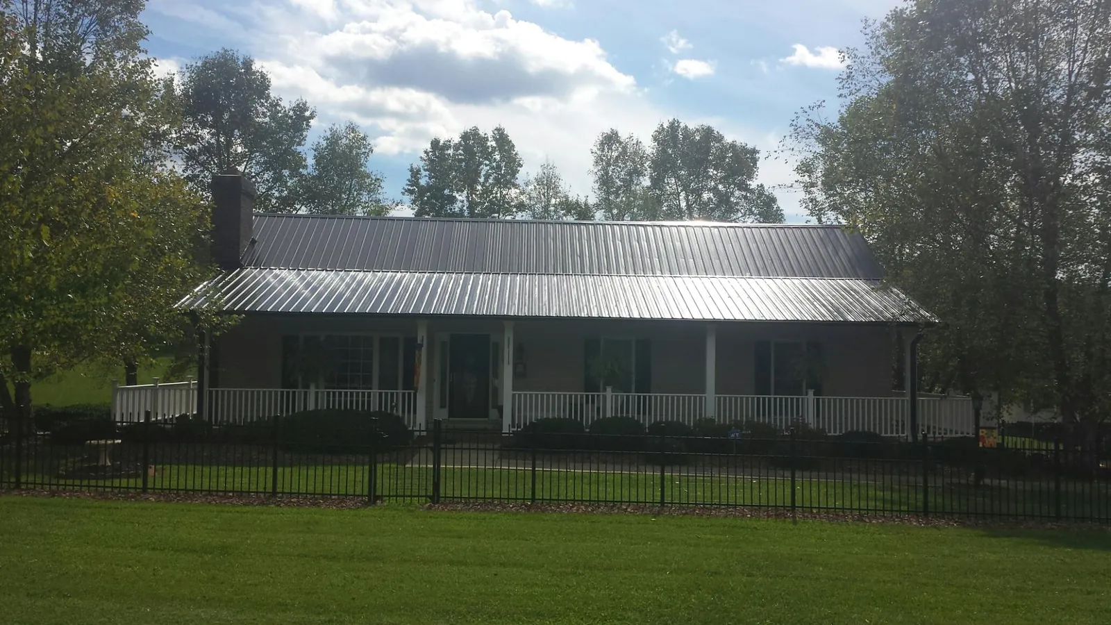 Gray metal roof on a brick ranch with a full width front porch — Gutter Guard Installation work by our crew in Elizabeth