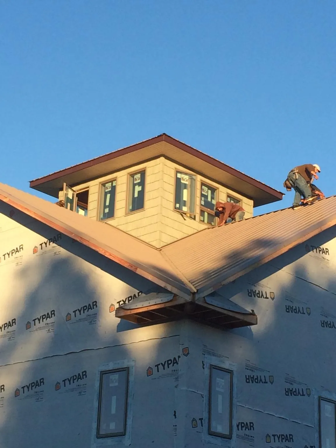 Roofers working around a rooftop cupola on a new metal roof at sunset — Roof Waterproofing in Elizabeth by Roofing Brothers
